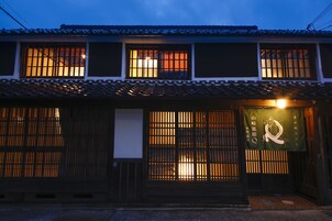 A traditional Japanese building with multiple windows, a tiled roof, and a signboard.