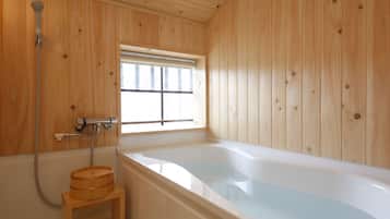 A wooden-paneled bathroom with a bathtub, a wooden stool, and a window.