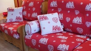 A wooden wall with a framed picture and a red sofa with heart-patterned cushions. - Apartment/ flat - ISOLA 2000 (Isola)