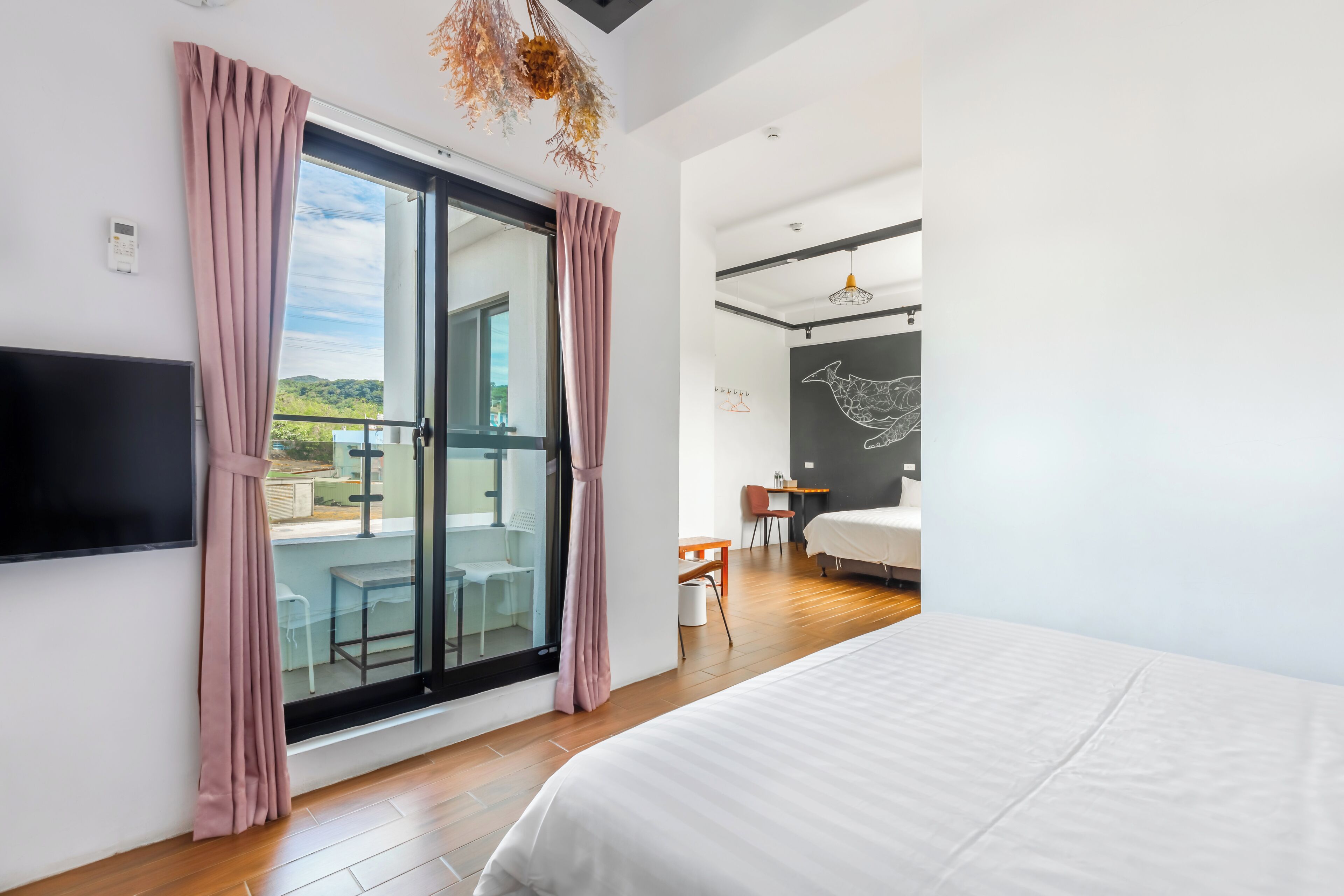 Una moderna camera d'albergo con un letto grande, una TV, un balcone con vista e una zona pranzo.