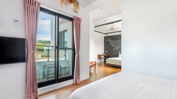 Una moderna camera d'albergo con un letto grande, una TV, un balcone con vista e una zona pranzo.