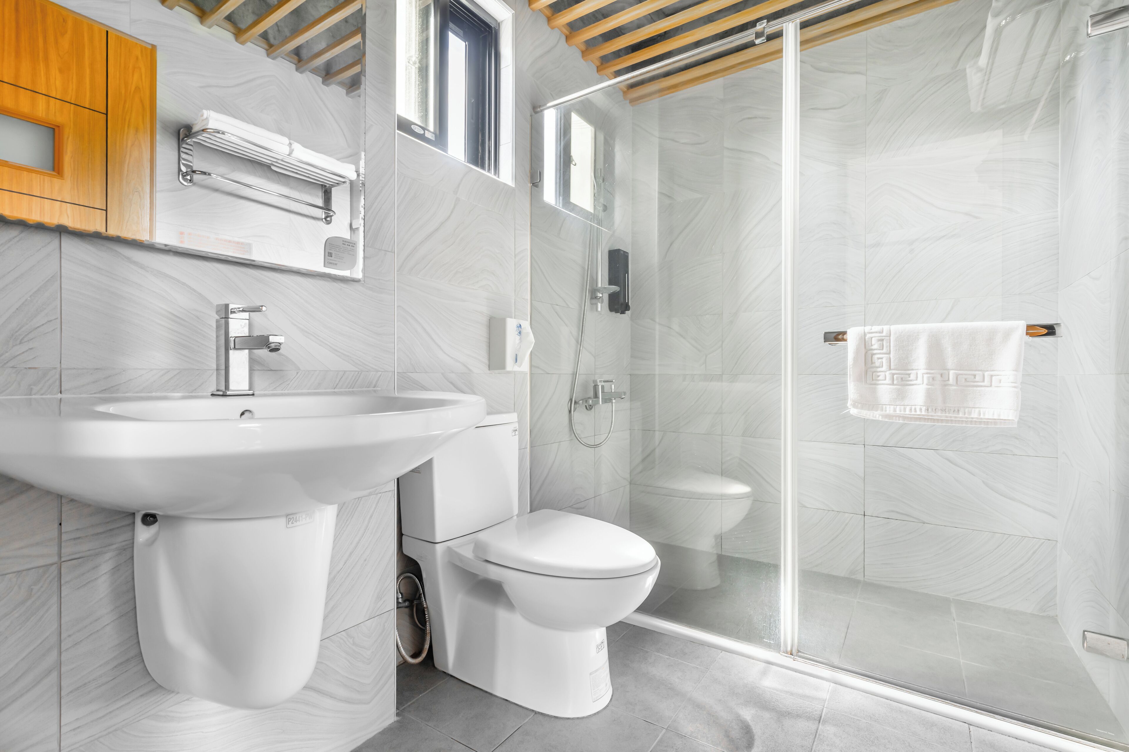 A modern bathroom with a white sink, toilet, and glass-enclosed shower.