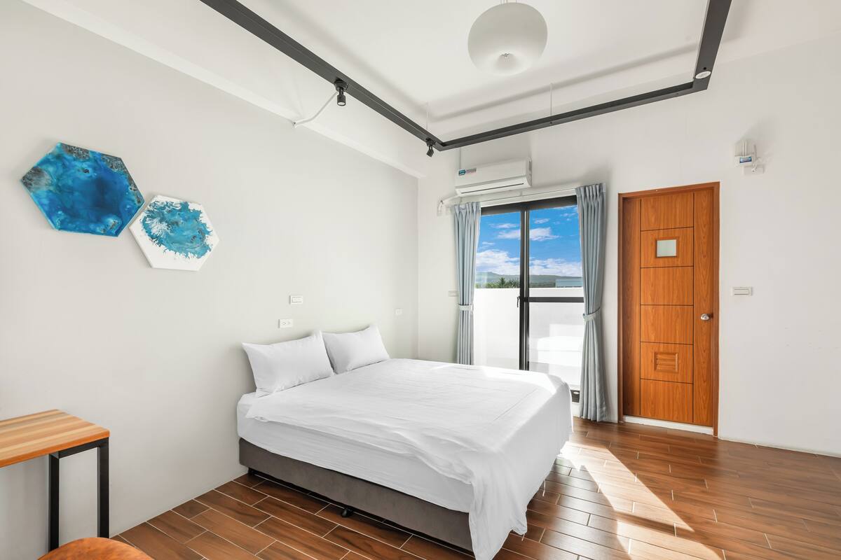 Un dormitorio moderno con una cama grande, una puerta de madera y vistas al exterior.