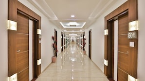 Un couloir d’hôtel avec des portes en bois, numérotées 501, et des plantes en pot.
