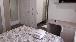 A bedroom with a bed, a desk, a TV, and a door leading to a bathroom. - Borgo Marinaro (Cetraro)