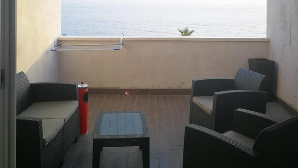 A balcony with wicker furniture, a small table, and a view of the sea. - Borgo Marinaro (Cetraro)