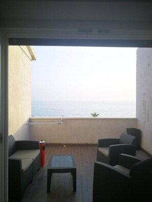 A balcony with wicker furniture, a small table, and a view of the sea. - Borgo Marinaro (Cetraro)