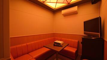 A corner room with a sofa, a table, and a television.