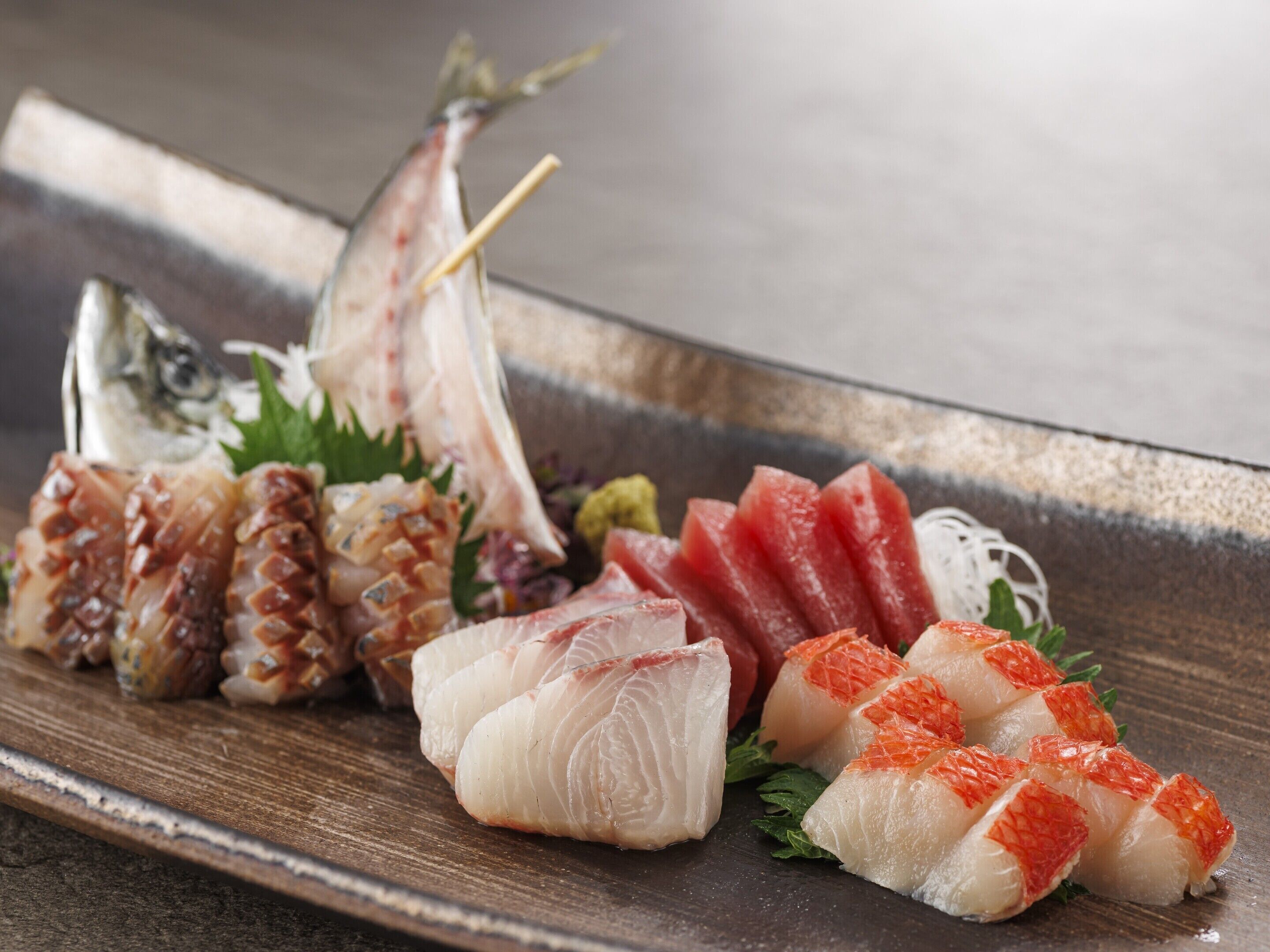 A variety of sashimi on a wooden serving board.