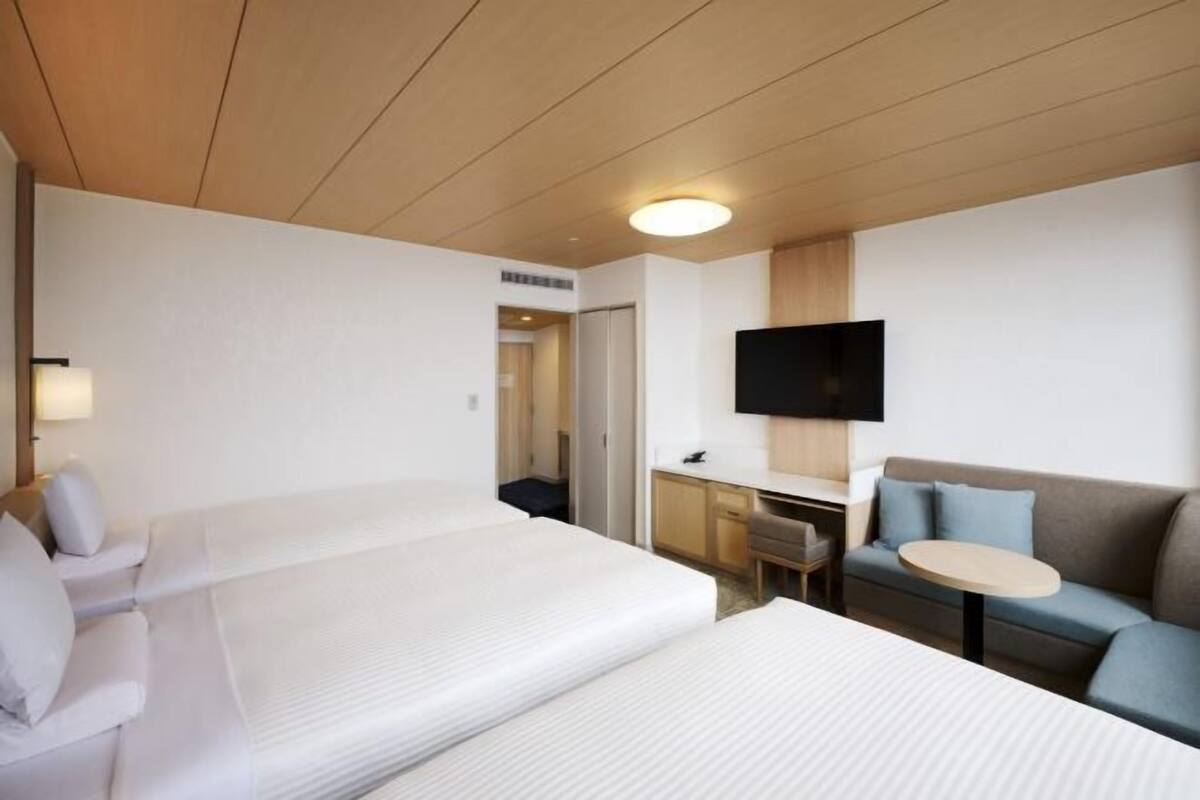 Una habitación de hotel con dos camas, un escritorio, un televisor y un sofá.