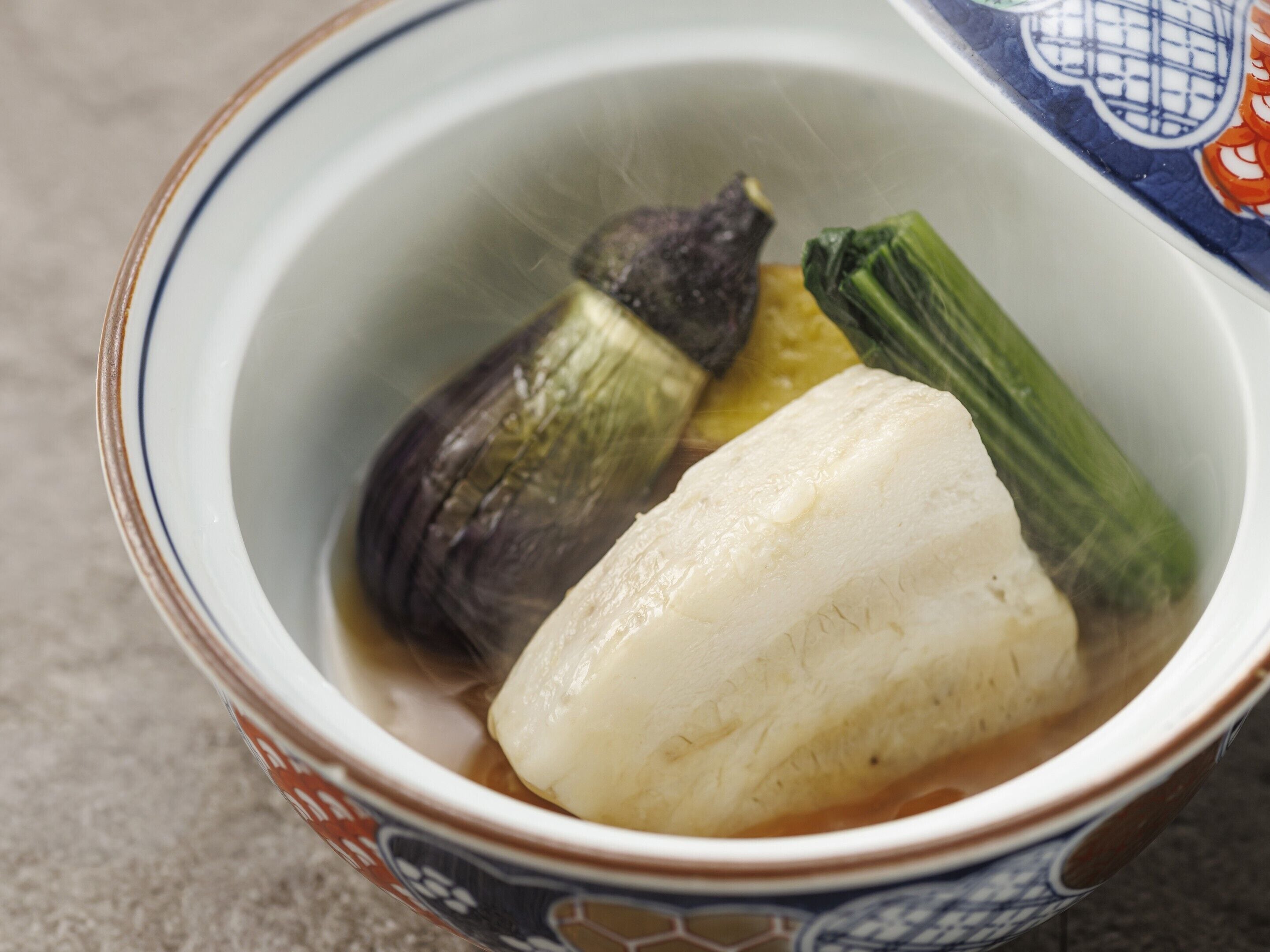 A bowl of soup with vegetables.