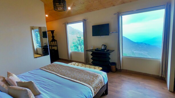 Une chambre dotée d’un grand lit, d’un téléviseur fixé au mur, d’un lavabo et offrant une vue sur les montagnes.