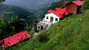 Un bâtiment situé sur une colline, avec un toit rouge, un balcon et un escalier menant à l’entrée.