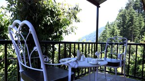 Un balcon avec deux chaises en métal blanc et une petite table, entouré d’une rambarde noire.