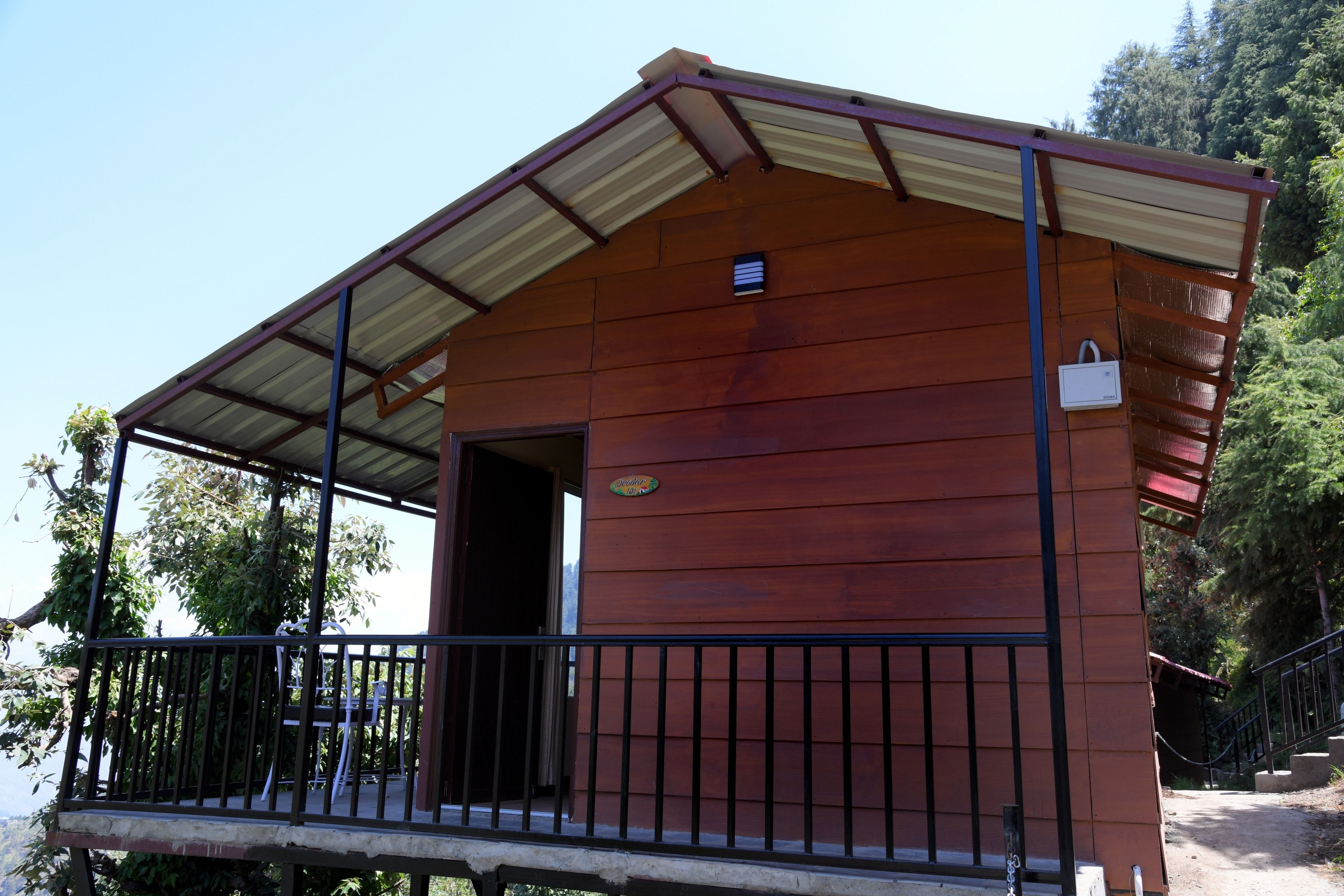 Una cabaña de madera con techo metálico y balcón.