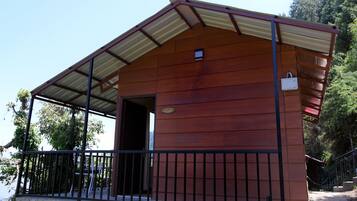 Una cabaña de madera con techo metálico y balcón.