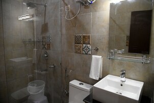 Un baño con ducha, inodoro, lavabo y espejo.