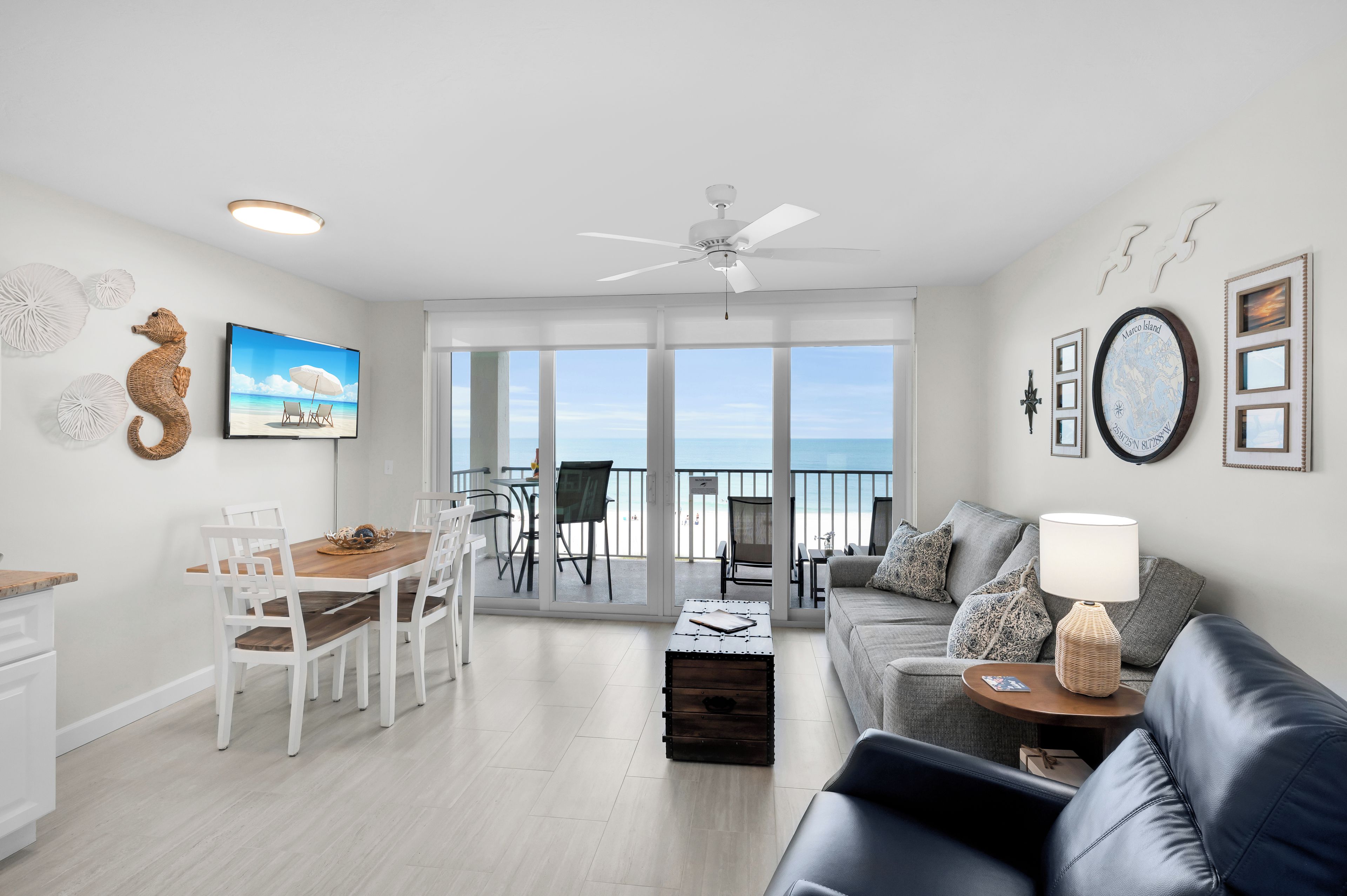 A modern living room with a balcony, a dining area, and a view of the sea.