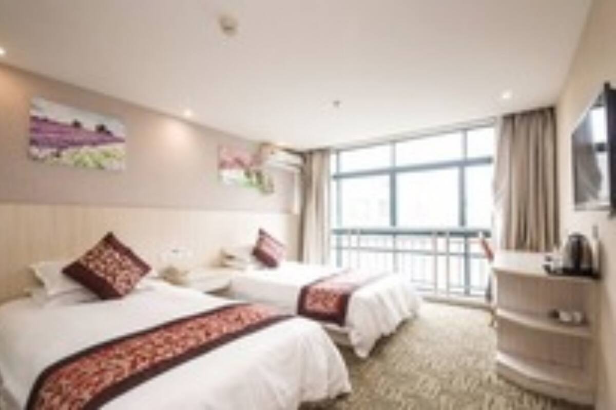 Habitación de hotel con dos camas, un ventanal grande y un televisor.