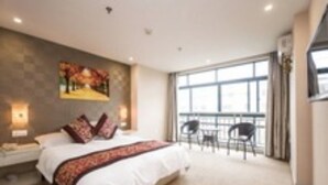 A hotel room with a large bed, a painting on the wall, a balcony with chairs, and a large window. - Gang Wan Yin Xiang Hotel (Jiaxing)