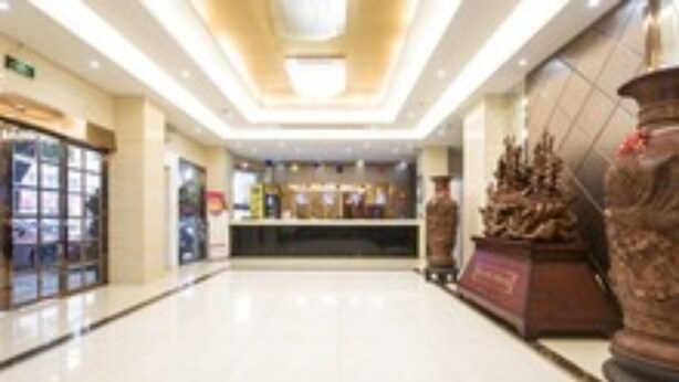 A hotel lobby with a reception desk, a large decorative sculpture, and a glass storefront. - Gang Wan Yin Xiang Hotel (Jiaxing)