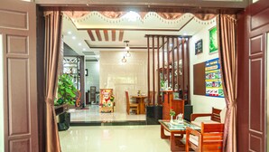 A well-lit, spacious room with a dining area, a sofa, and a TV. - Golden Soulmate Homestay (Da Nang)