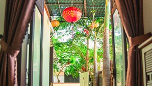 An open doorway leading to a covered outdoor area with a tiled floor, a potted plant, and a red lantern. - Golden Soulmate Homestay (Da Nang)