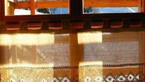 A window with a view of a snowy landscape and a wooden cabin. - Hotel Garni Plueme (Sauris)