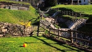 A rural village with stone pathways, wooden fences, and houses with sloped roofs. - Hotel Garni Plueme (Sauris)
