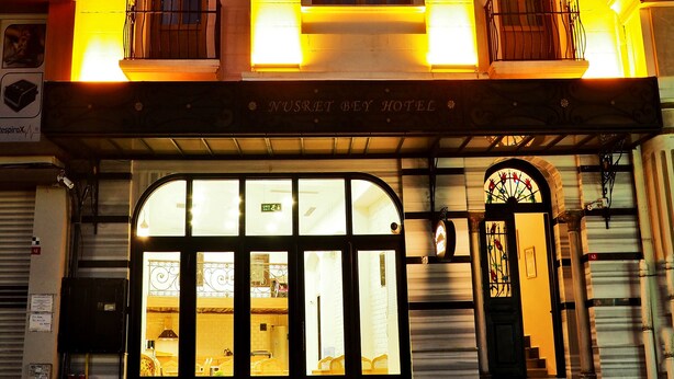 A hotel facade with multiple balconies, large windows, and a prominent entrance. - Nusret Bey Hotel (Istanbul)