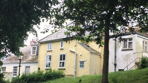 A yellow building with multiple windows and a tree in front. - Saffron House (Fowey)
