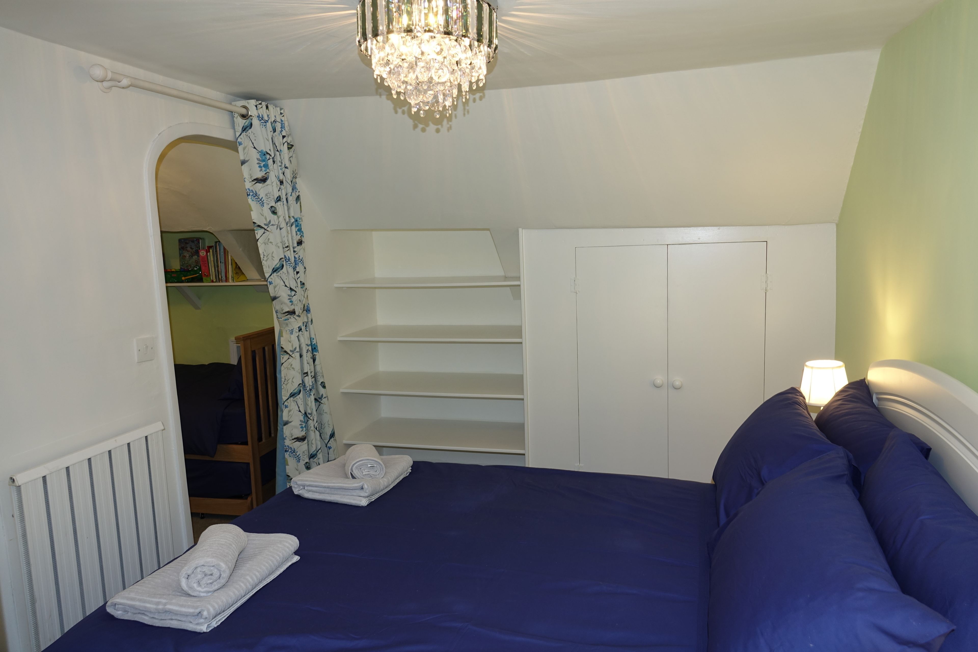 Un dormitorio con cama, armario, radiador y candelabro.