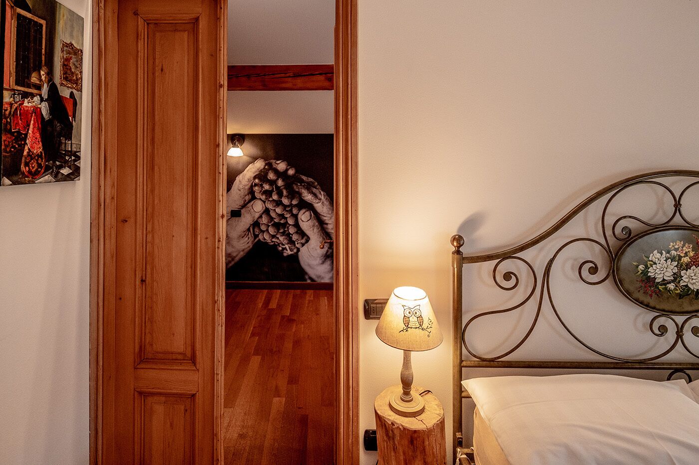 Una camera da letto con una porta in legno, un letto con testiera in metallo, un comodino con una lampada e una parete con un quadro incorniciato.
