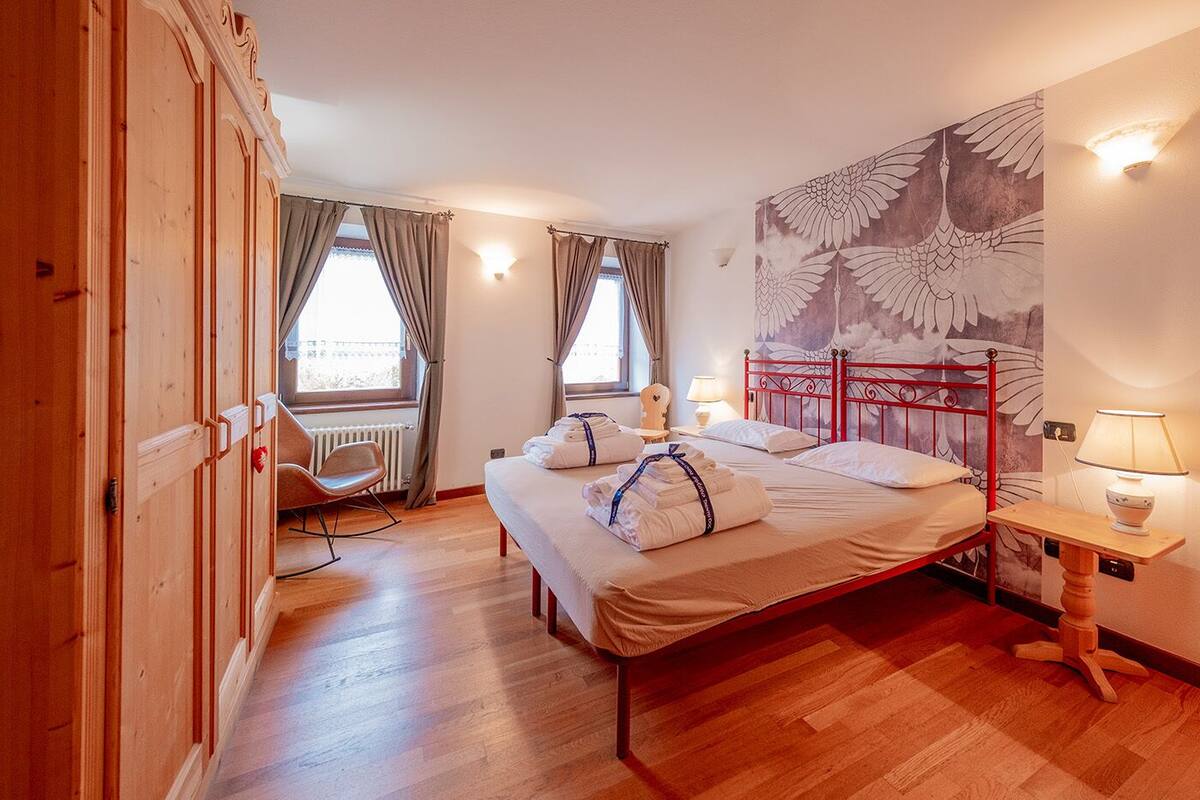 Una habitación de hotel con cama, una silla, un escritorio y un mural grande en la pared.