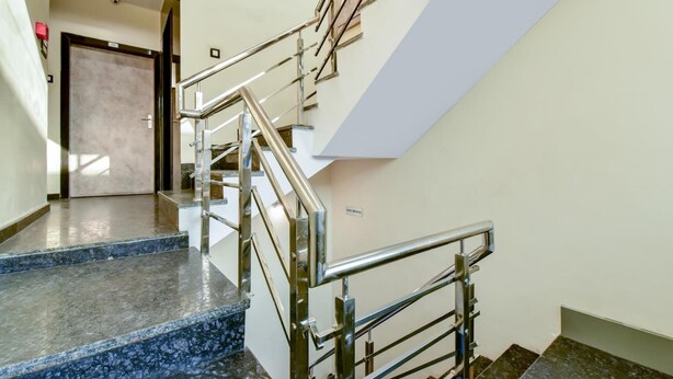 Una escalera moderna con barandillas de metal y escalones de granito, que conduce a una puerta con la inscripción 'B&B ROOMING'.
