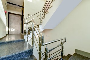 A modern staircase with metal railings and granite steps, leading to a door labeled "B&B ROOMING." - Hotel Frontier Royal (Kota)
