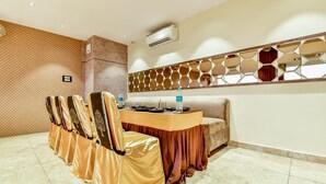Un salón de conferencias con una larga mesa, sillas, un sofá y un panel decorativo en la pared.