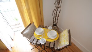 A dining table with yellow placemats, white plates, and cutlery, set against a wooden floor and a white wall.