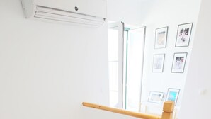 A wooden staircase with a handrail, a small window, and a wall-mounted air conditioner.