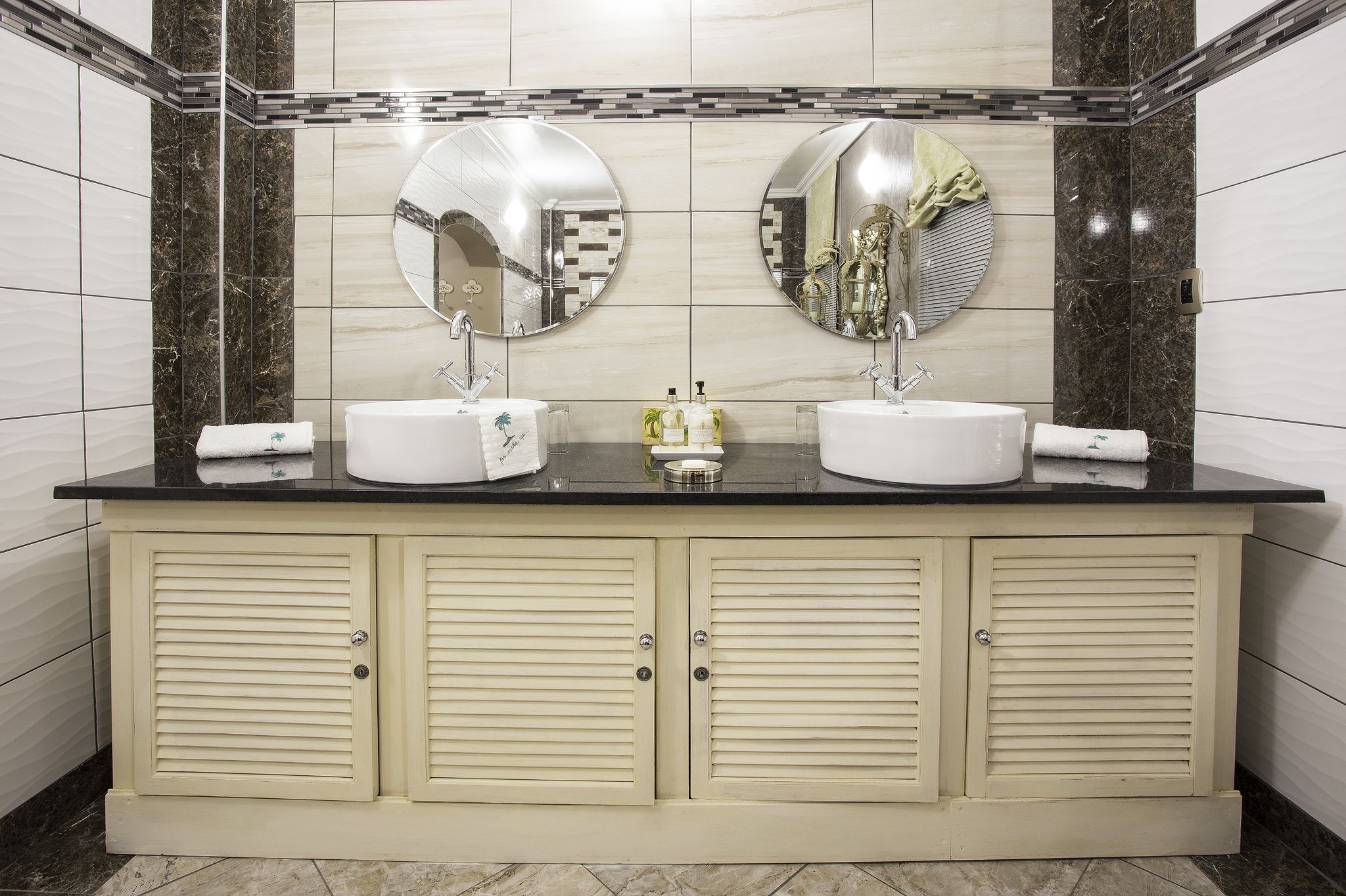 Un baño con dos lavamanos, un espejo sobre cada uno y un mueble debajo.