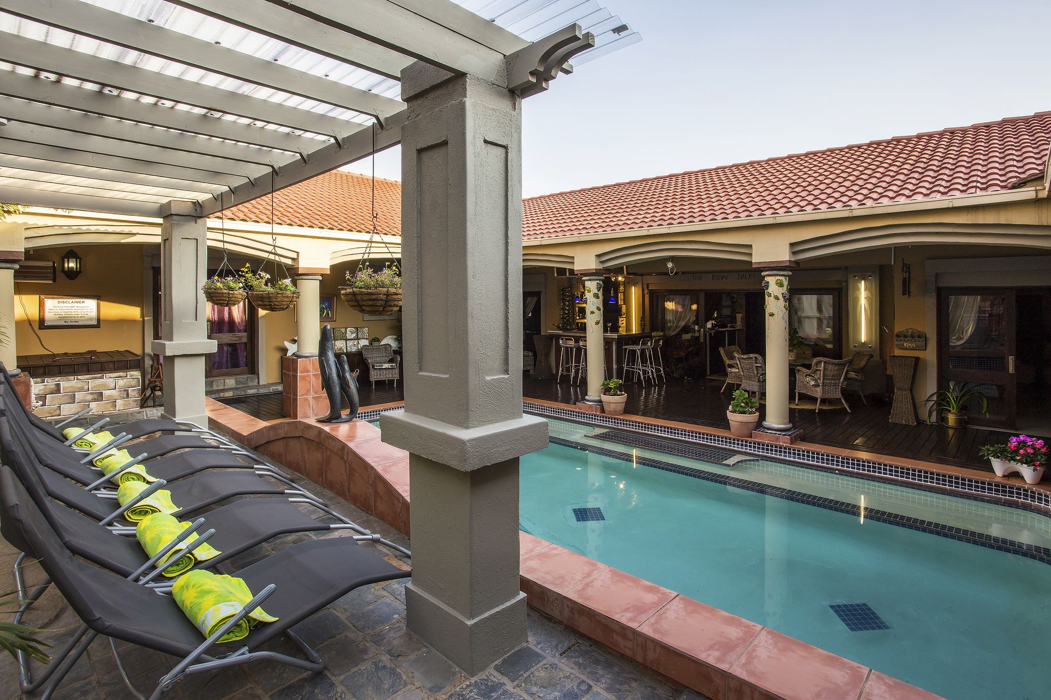 A pool area with lounge chairs, a covered seating area, and a bar.