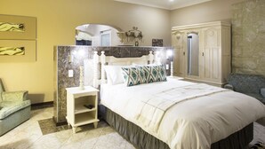 Une chambre à coucher avec un grand lit, une table de chevet, une commode, une chaise et un miroir.