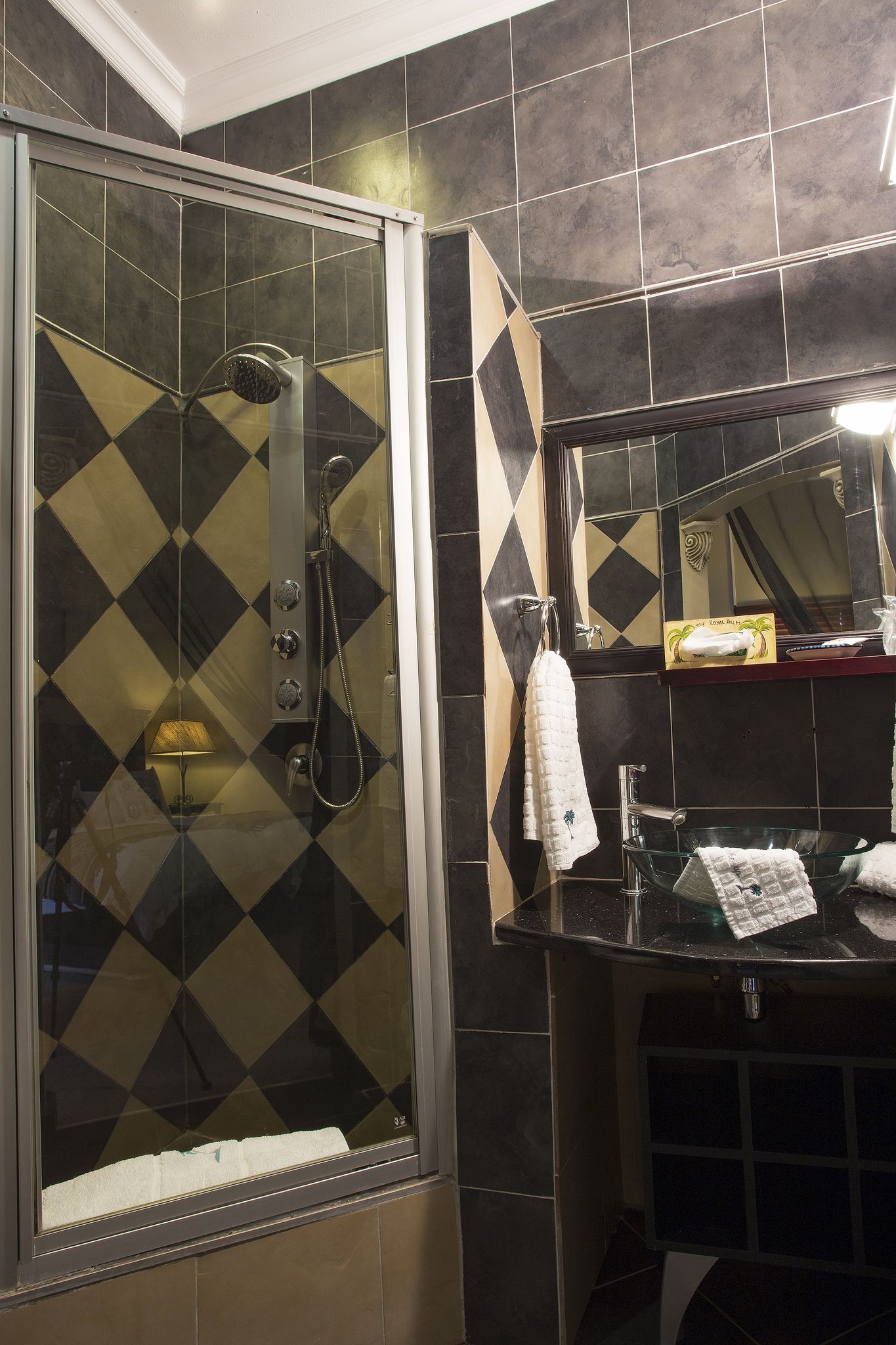Een badkamer met een glazen douchecabine, een wastafel met spiegel en een handdoekrek.