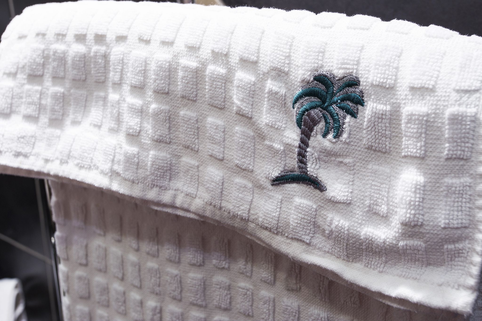 Une serviette blanche ornée d’un motif de palmier brodé.