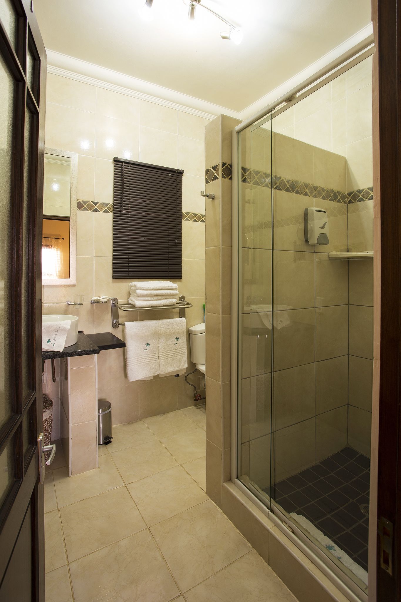 Un baño con ducha de vidrio, lavamanos con toallero y retrete.
