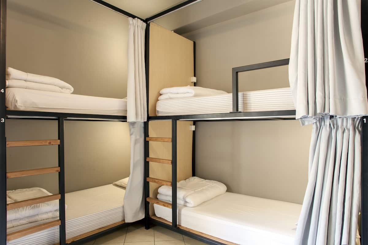 Ein Eckzimmer mit Etagenbetten, einer Holzleiter und einem Nachttisch mit Lampe.