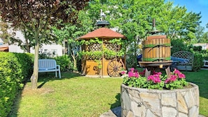 A garden with a gazebo, a wooden birdhouse, and a bench. - Regenbogen Appartement (Bad Krozingen)