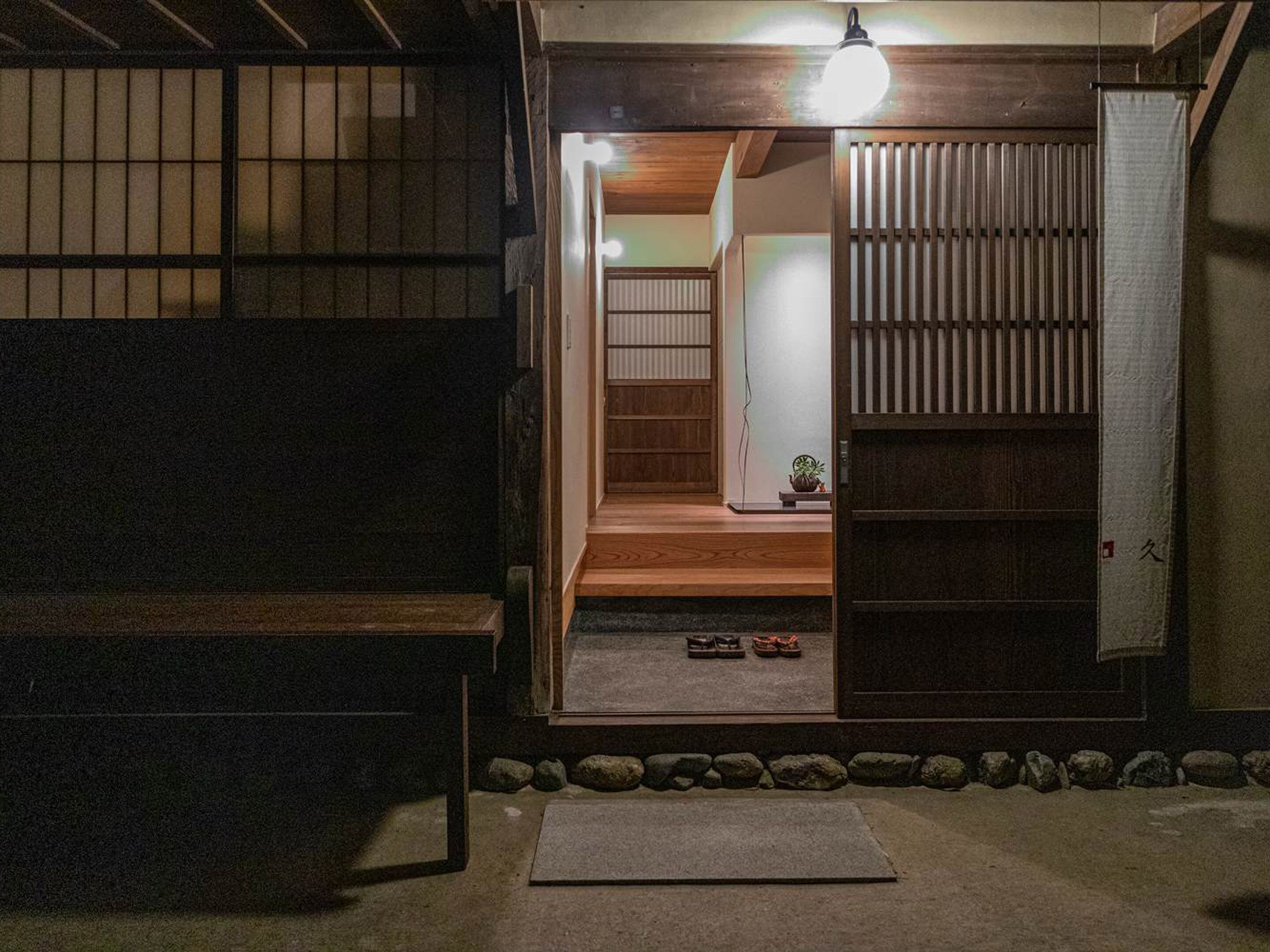 A traditional Japanese-style room with tatami flooring, a sliding door, and a small wooden bench.