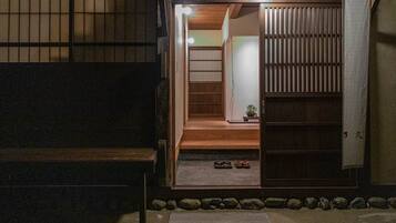 A traditional Japanese-style room with tatami flooring, a sliding door, and a small wooden bench.