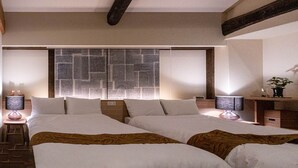 A bedroom with two beds, a stone wall, and a desk with a lamp. - UCHIKO-Inn HISA (Uchiko)